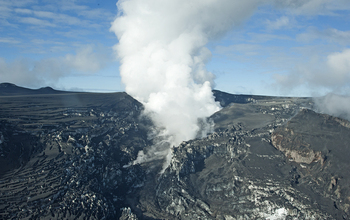 The glacier is covered with volcanic ash, and steam rises as glacial meltwater meets lava flow.